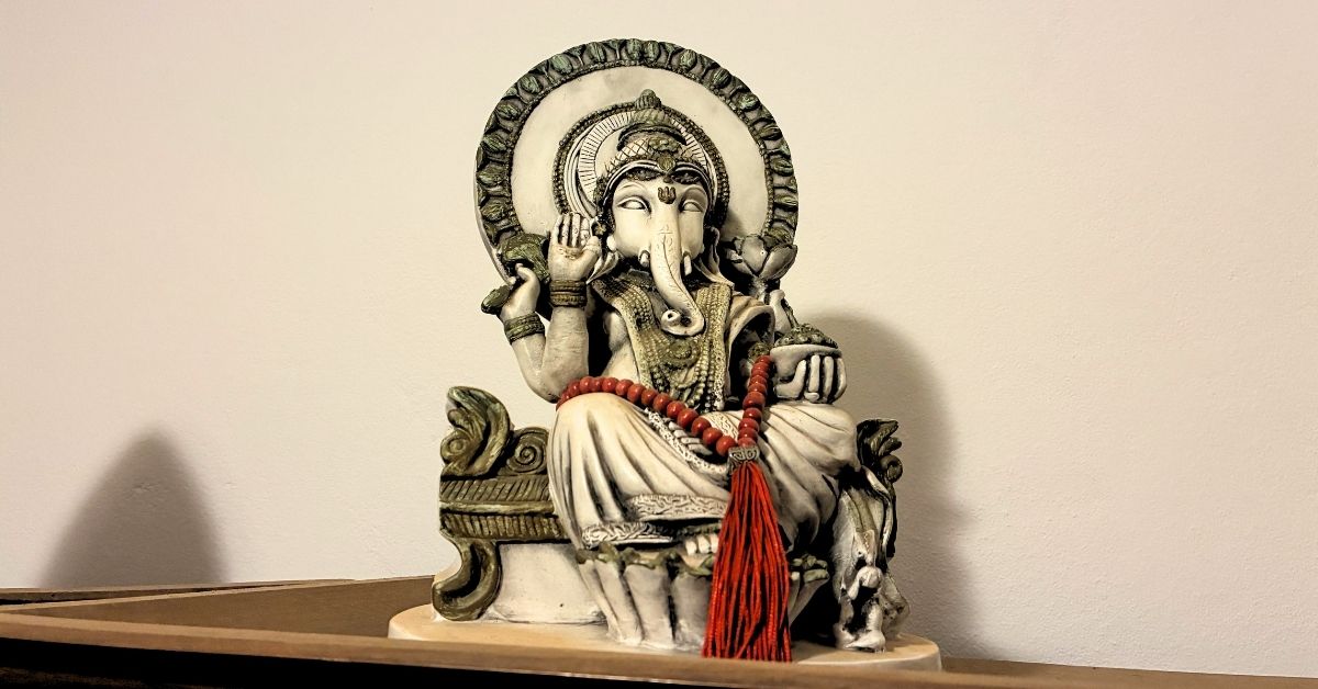 Estátua branca de Ganesha com um japamala vermelho